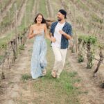 an engaged couple running through the vineyard